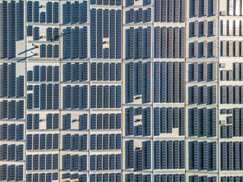 Aerial view of a sprawling industrial complex covered in countless dark solar panels, creating a stark geometric mosaic on the bright rooftops, Vagos, Aveiro, Portugal.