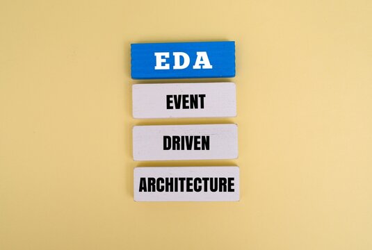 Wooden blocks stacked witht EDA - Event Driven Architecture text. IT, software development, and digital transformation concepts