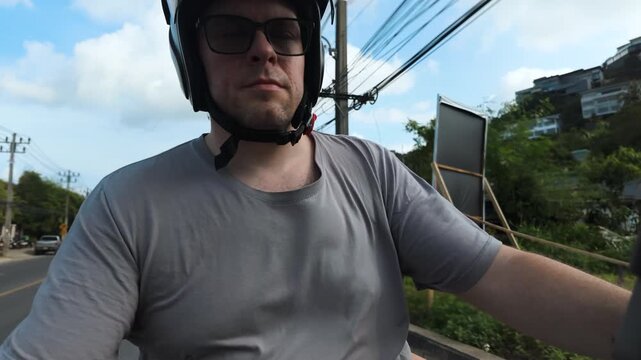 Man Riding Scooter Through Urban Street in Koh Samui Thailand