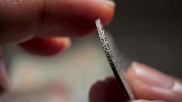 Close up video of an antique Mexican 2 reales coin being physically inspected by hand. The footage highlights the crowned shield, pillar elements, engraved surface, and aged silver appearance.