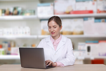 Fototapeta premium Pharmacist using laptop at table in drugstore