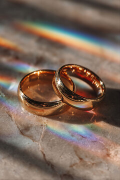 Elegant Gold Wedding Rings with Rainbow Light Reflections Symbolizing Inclusive Marriage