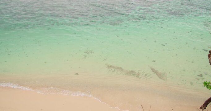 Tropical turquoise ocean water meeting sandy beach shore in Uluwatu Bali Indonesia