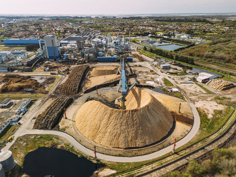 Aerial view of a massive woodchip pile dwarfing the industrial landscape near the factory, a contrast of raw material and manufactured output, Cacia, Portugal.