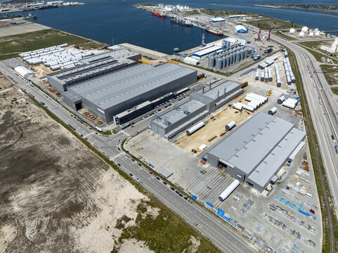 Aerial view of industrial buildings casting long shadows near the port, where red ships stand out against the blue water, Aveiro, Aveiro, Portugal.