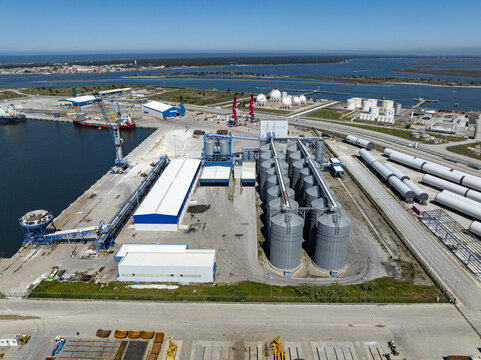 Aerial view of the industrial port with towering silos and gleaming storage tanks, contrasting against the deep blue harbor waters, Aveiro, Aveiro, Portugal.
