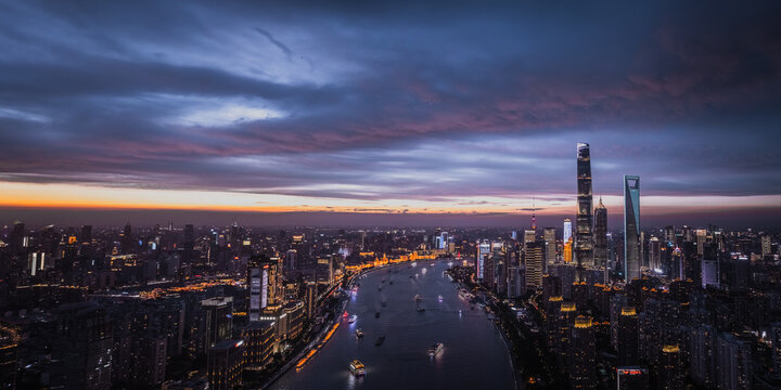 Aerial view of city lights twinkle along the river as dusk paints the sky in hues of blue and orange, Shanghai, China.