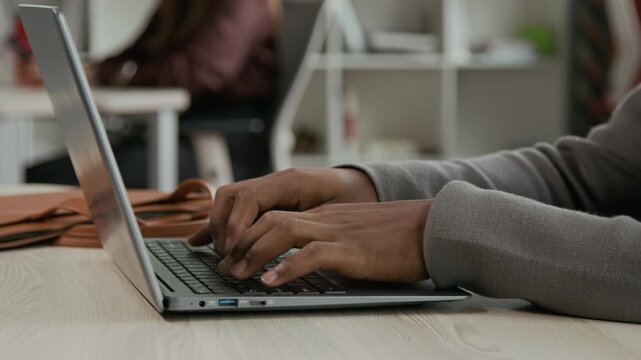 Close up shot of hands of unrecognizable African American office worker typing on laptop keyboard at desk