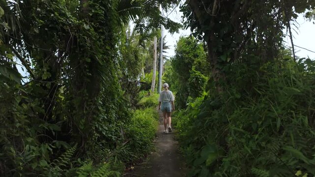 Woman Walking Along Jungle Path Through Rice Fields in Ubud Bali