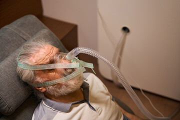 Elderly man with breathing mask resting indoors at night © Svitlana