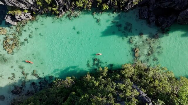 aerial view of a kayak on crystal clear turquoise water. Drone descending over the Big Lagoon in El Nido, Palawan nature, Philippines.