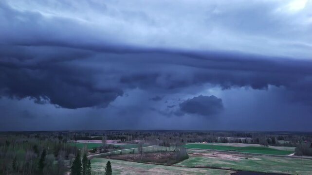 Approaching thundercloud formation creating a dramatic heavy atmosphere over land in aerial view