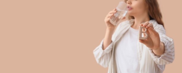 Obraz premium Young woman taking vitamin B on beige background with space for text