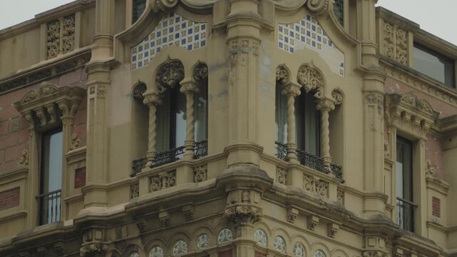 Stunning ornate corner building facade in Gijon, Spain, featuring detailed stone carvings, decorative columns, wrought iron balconies and classic early 20th century European architecture.