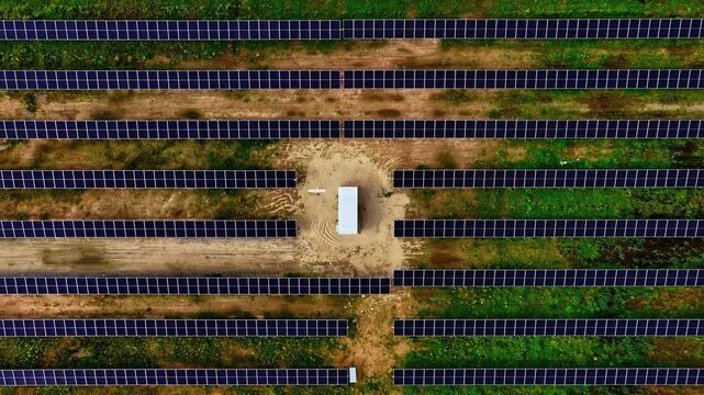 Solar power modules generating renewable energy in rows across open land, featuring a transformator box
