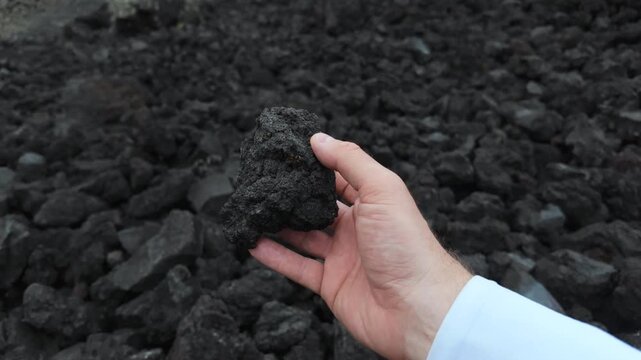 Hand Picking Up and Turning a Piece of Volcanic Lava at Mount Batur Bali