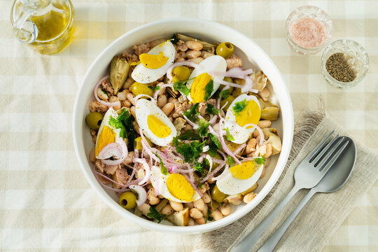 Cannellini Bean Salad with Tuna and Eggs on Checkered Tablecloth with Olive Oil and Cutlery