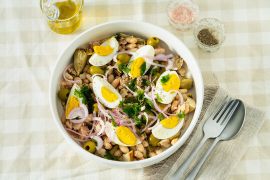 Cannellini Bean Salad with Tuna and Eggs on Checkered Tablecloth with Olive Oil and Cutlery