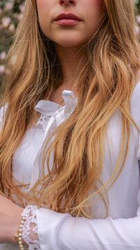 Close-up of a young woman's face with flowing blonde hair and delicate white lace details
