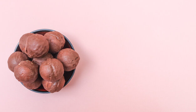 Chocolate candy ball with peanut filling in a bowl isolated on pink background. Chocolate candy balls with rich peanut filling served in a bowl