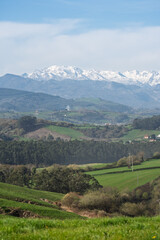 Naklejka premium Vertical View of Snowy Mountains and Green Rural Valley