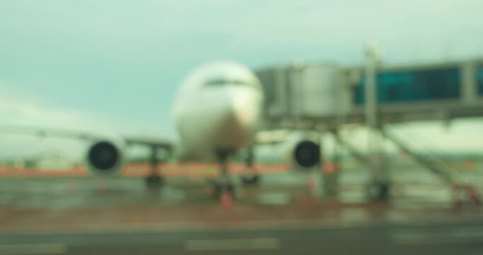 Defocused view if commercial aircraft attached to jet bridge for passengers in Airport