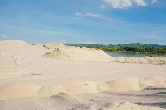 View of large piles of white sand at a quarry near the riverbank under a blue sky in Futog, Vojvodina, Serbia.