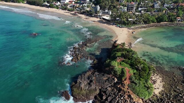 Drone shot of Parrot Rock connected to the mainland by a narrow sandbar. Mirissa, Sri Lanka