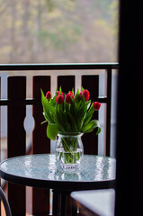 Bukiet czerwonych tulipanów ustawiony w pokoju hotelowym. Dekoracyjne kwiaty ocieplają wnętrze i podkreślają przytulny, elegancki charakter miejsca noclegowego. © Freshfanpage
