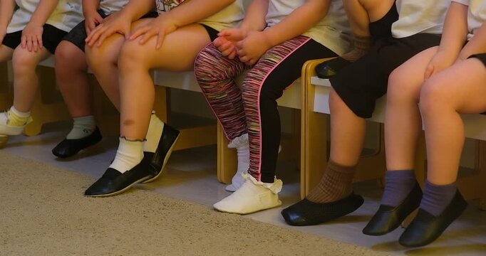 Moskow, Russia, 21.08.2025 Group of children sitting on bench in classroom. Kindergarten pupils waiting for activity. Boys and girls rest during break time in preschool indoor setting.