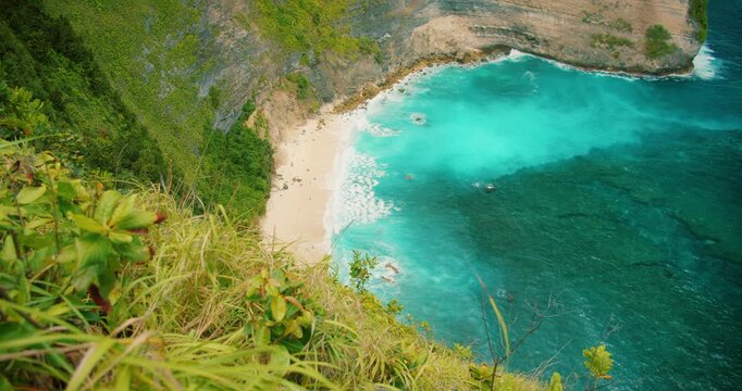 Wide coastal view of sandy beach below cliffs and ocean in Nusa Penida Bali