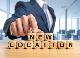 Obraz premium New Location - Geschäftsmann zeigt auf den Text 