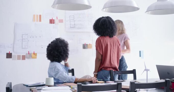 Camera revealing, diverse women designers at office reviewing plans and swatches to finalize design