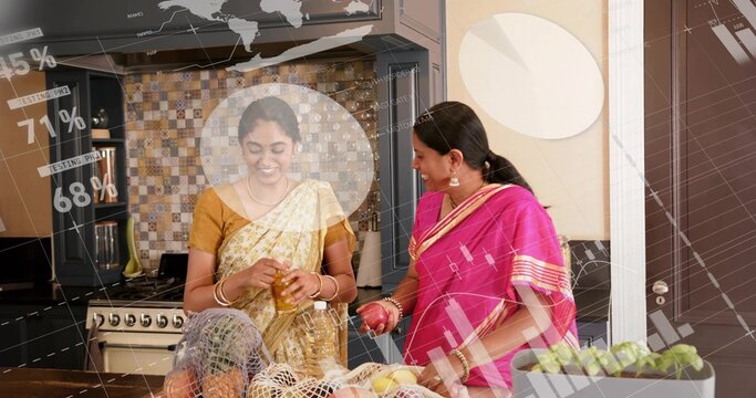 Smiling mother and daughter preparing food at kitchen island, holding jar, red fruit, sarees