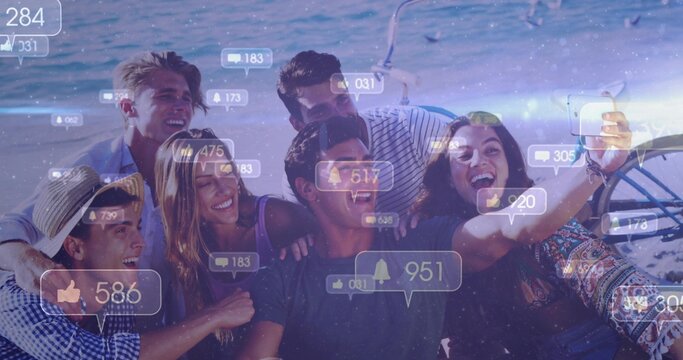 Laughing six friends wearing casual clothes, leaning on boat, holding phone with social icons, helm