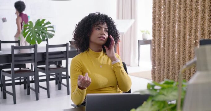 Adult African American woman in mustard top using pink phone reaching paper at desk clarifying doc