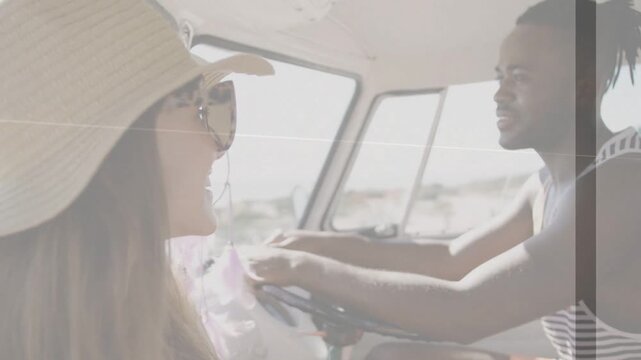 Couple laughing while driving van on coast, driver holding steering wheel, straw-hat holding lei