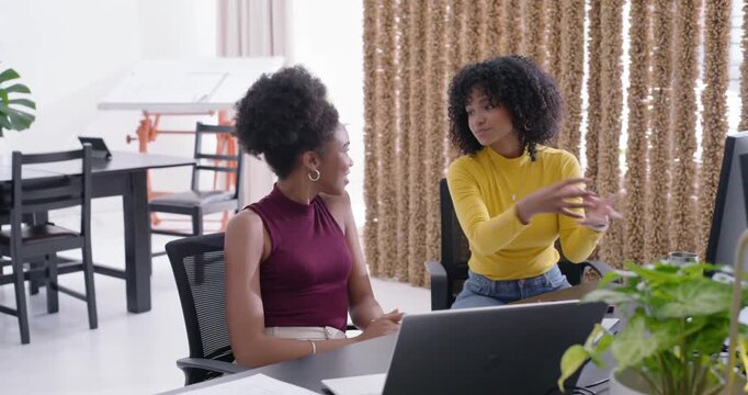 Diverse female duo burgundy top opening laptop yellow top pointing sharing ideas office monitor