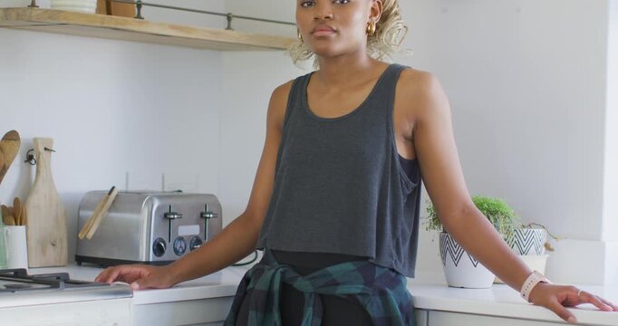 Leaning at kitchen counter, African American woman smiling, laughing at off-camera cue by toaster