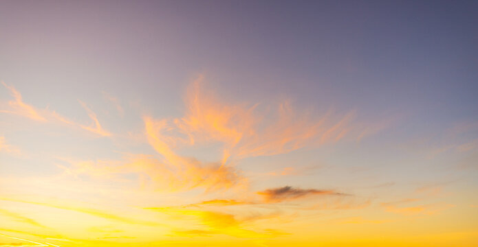 Dramatic Golden Sunset over Scattered Clouds with Blue Sky Gradient,A breathtaking sunset scene featuring a vibrant orange sun setting on the horizon, illuminating scattered cumulus clouds with golden
