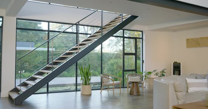 Camera is tracking right, revealing staircase and sofa, showcasing interior and planted patio