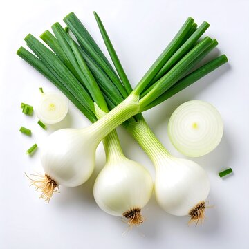 Overhead shot of three fresh spring onions with green stalks, roots, and two onion halves on white background