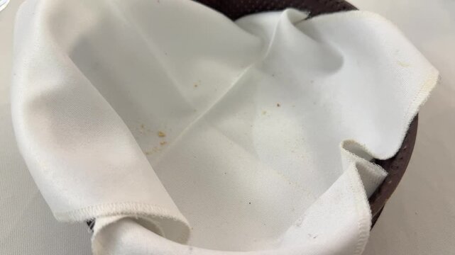 Taking bread roll from basket with white napkin, close up restaurant scene