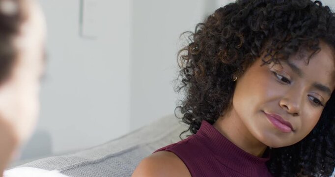 Woman listening to voice, closing eyes, mulling words, opening eyes, focusing on couch, maroon top