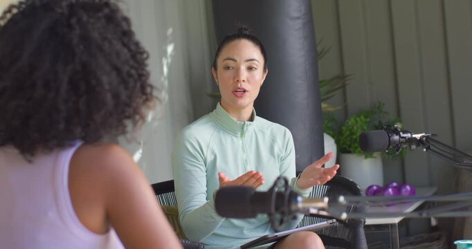 Female hosts podcasting in studio, green-top host explaining points after cohost cue, using mic