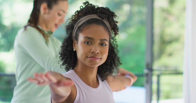 African American woman holding arm pose at home with headband after trainer cueing and fixing form