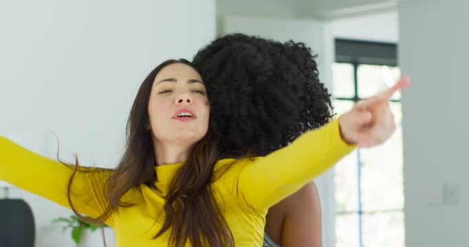Asian African American women one raising arms rotating back-to-back home practicing in yellow top