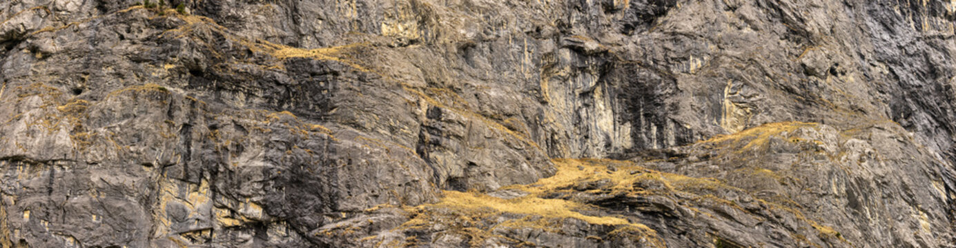 Image panoramique montrant une paroi rocheuse imposante aux textures brutes et irr&eacute;guli&egrave;res domine le paysage. Pouvant servir de texture et d'arri&egrave;re-plan