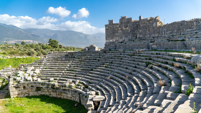 Ancient Roman theater ruins at Xanthos in Lycia, Mugla, Turkey. Stone semicircular seating tiers overlooking a mountain landscape