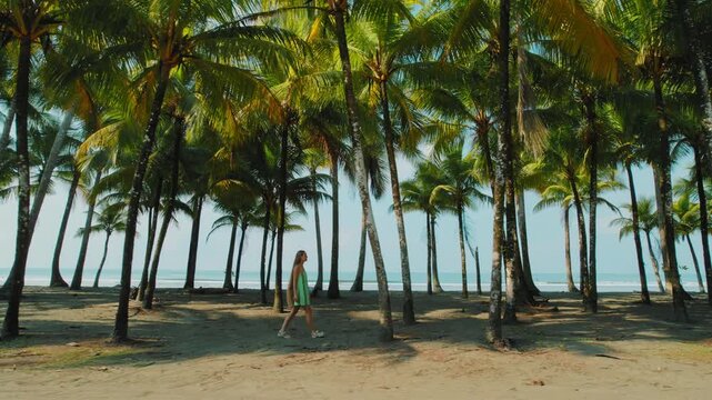 Woman walking under tall palms toward a peaceful tropical beach scene